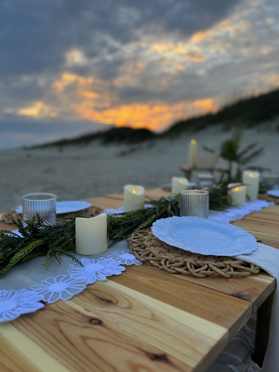 Beach table place setting with greenery runner and candles
