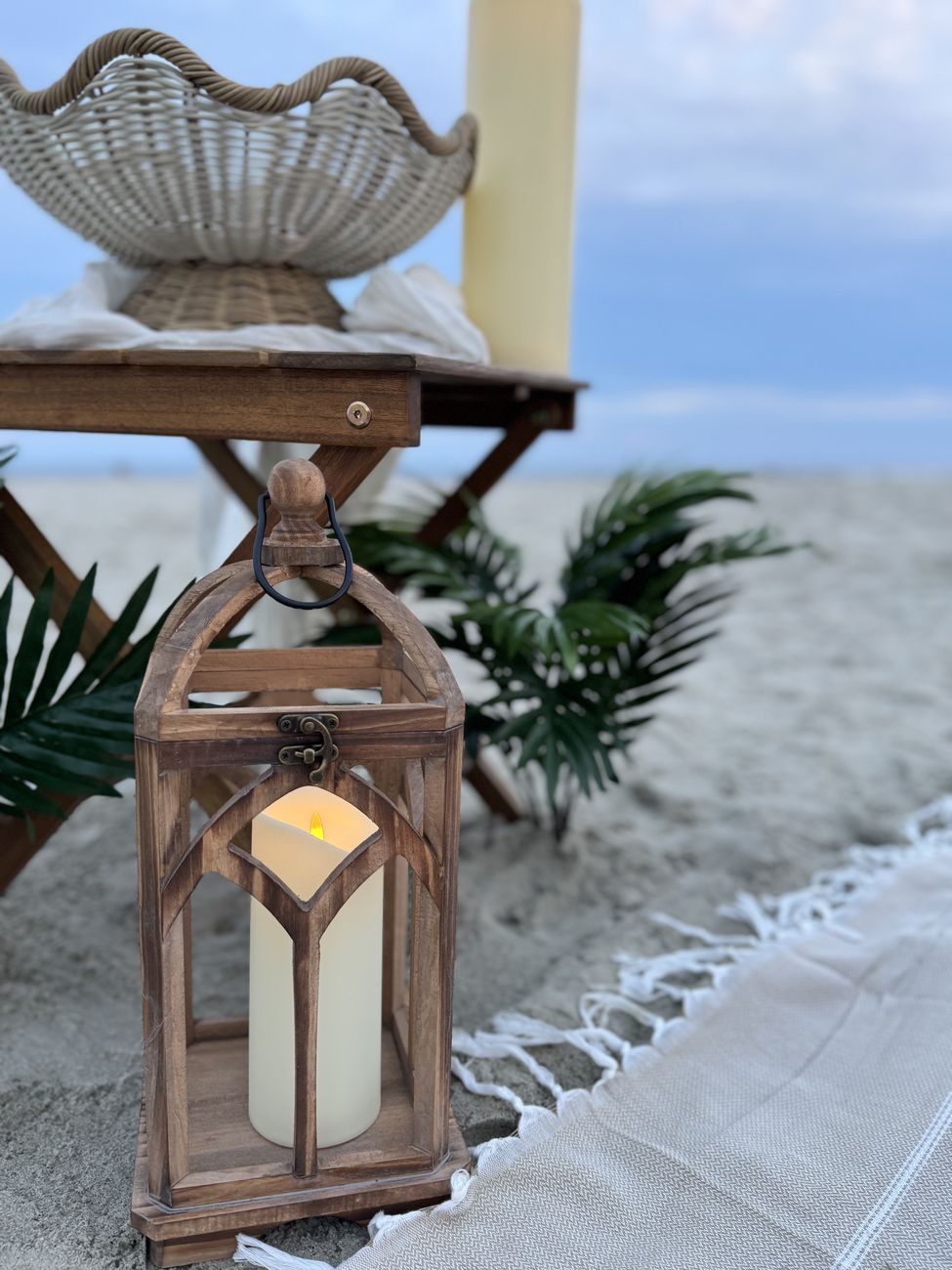Wooden lantern with candle glowing on the beach at dusk